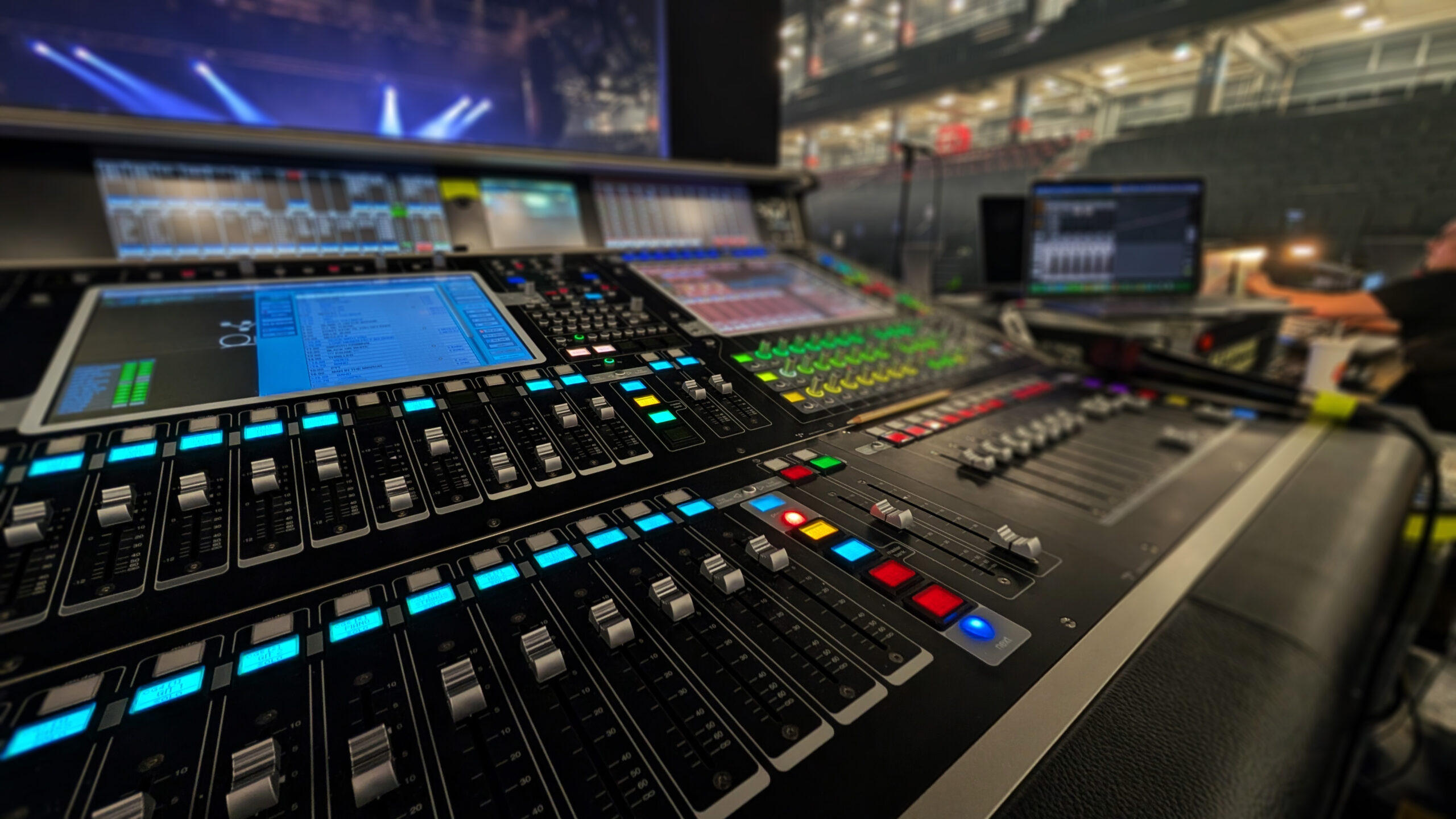 DiGiCo Quantum 7T Mischpult in einer Veranstaltungshalle." "Nahaufnahme eines DiGiCo Quantum 7T Audiomischpults mit beleuchteten Reglern und Bildschirmen.